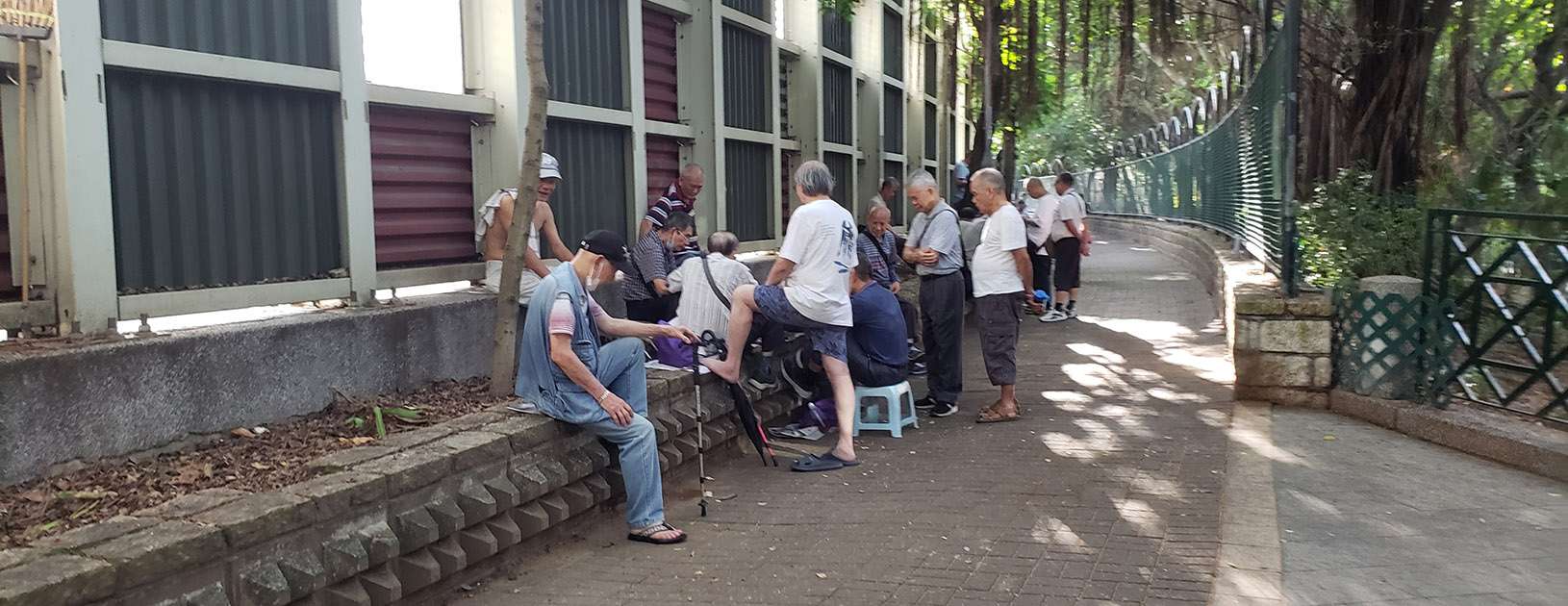 Elderly men gathered just outside a park entrance to play card games 牌友們聚集在一個公園的入口處